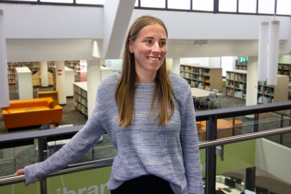 A smiling Maddie Hickey in the uni library discussing how to get early entry into university