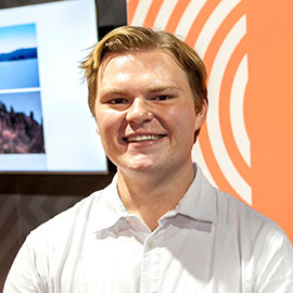 Charles Sturt student Dav Francis standing in front of an orange banner