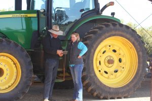 James Stephens, Charles Sturt's farm manager and Dr Alison Southwell looking at digital agriculture information on an iPad while standing in front of a large tractor.