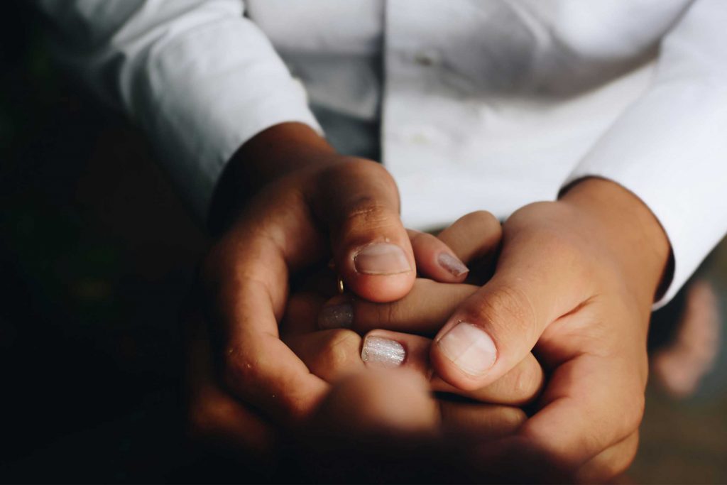 Close up of one person cupping another's hand in support. Casey Dodd pursued a nursing career to help and to heal.
