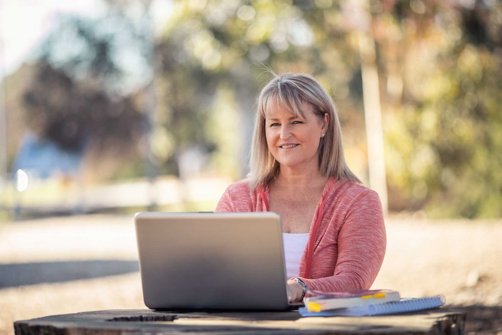 Francine Lee launched into a new career. She's pictured at an outdoor table working at her laptop.