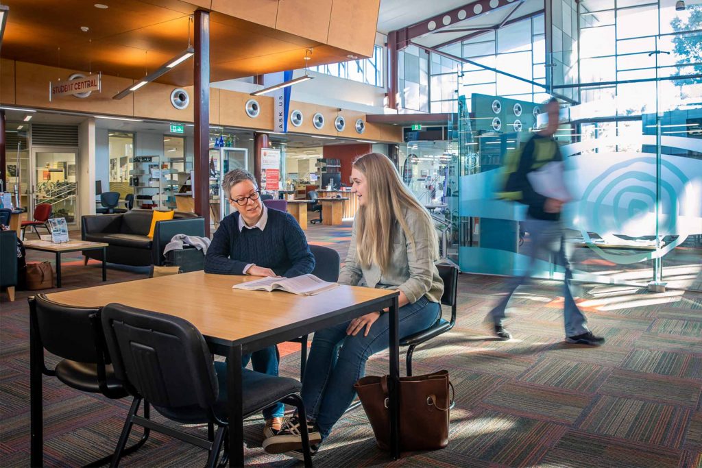 Two students sitting at a library table studying. These facilities can be used by Charles Sturt University online law students.