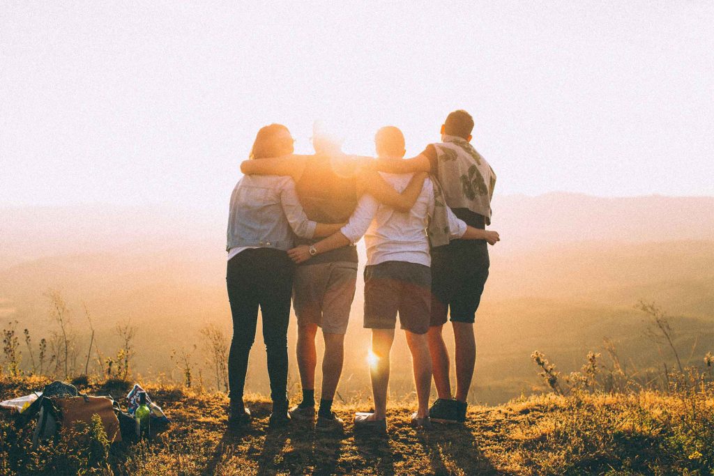 Four young people watch the sunrise over the mountains. They may be contemplating six things about uni life they wish they'd known in high school.