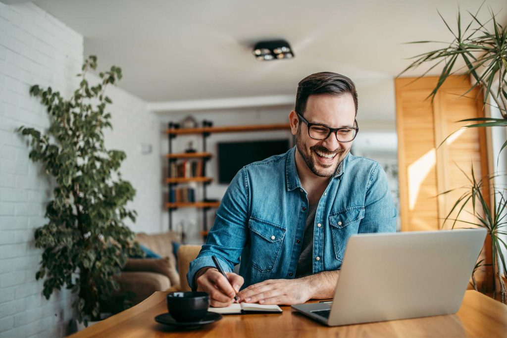 Happy male online student studying at his laptop