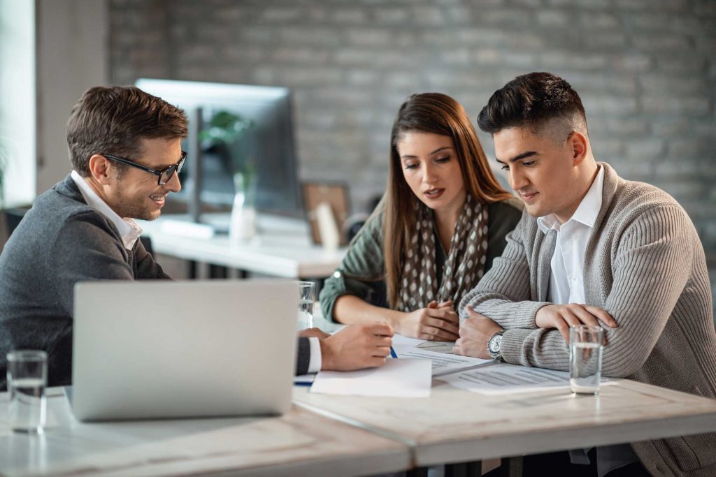 Smiling male financial planner providing advice to young professional couple
