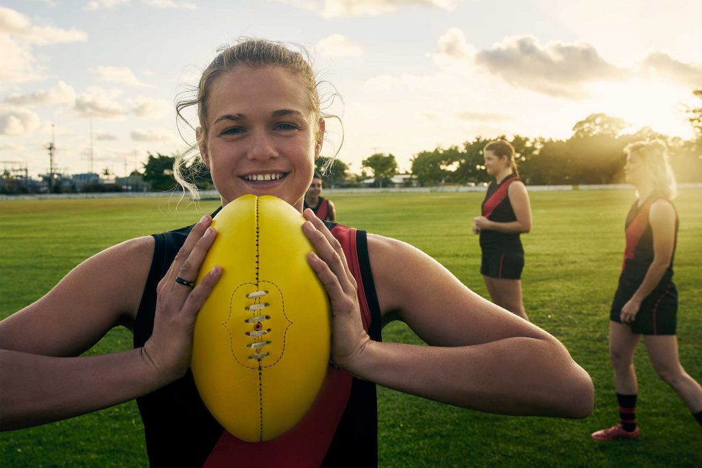 Smiling young female football player with team mates in background