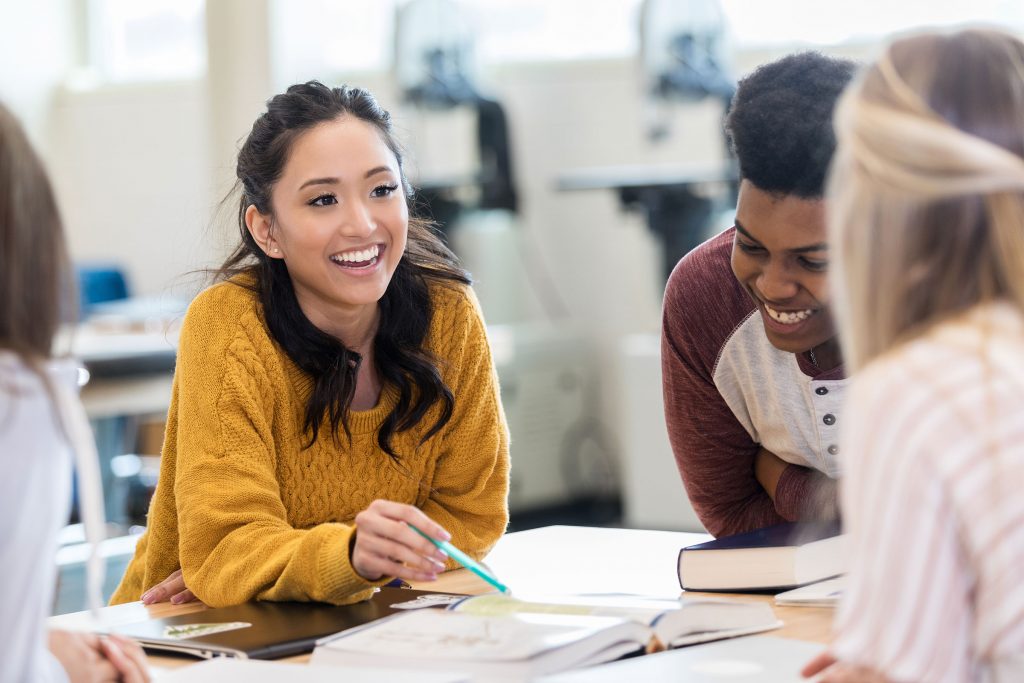 Smiling female student using her soft skills to collaborate with classmates
