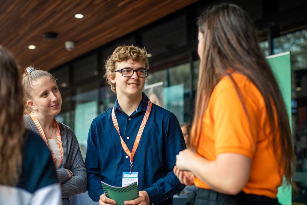 Smiling first year uni students listen to support services staff