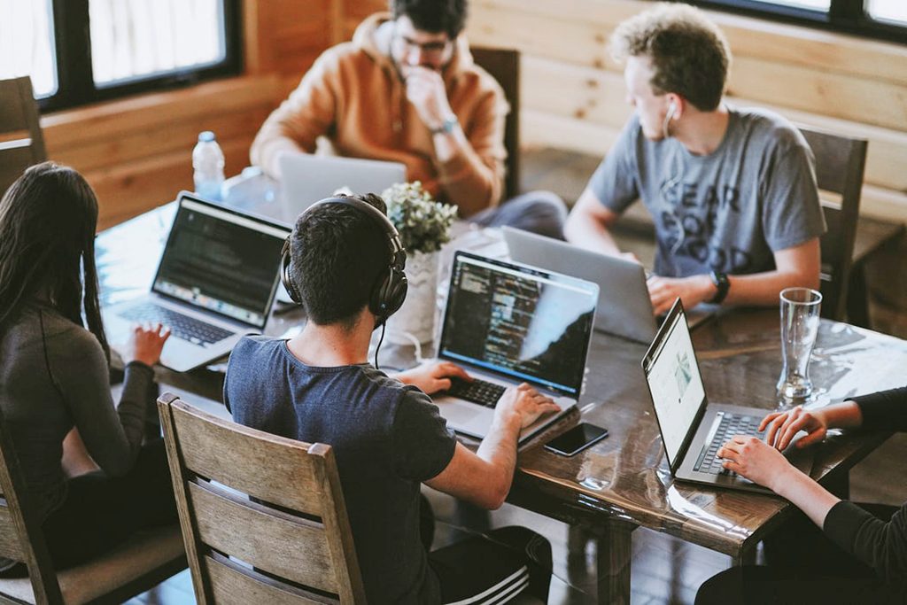 A group of people working on laptops looking at cyber security code.