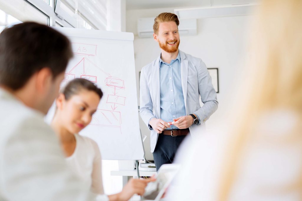 Man at whiteboard talking to people about skill development