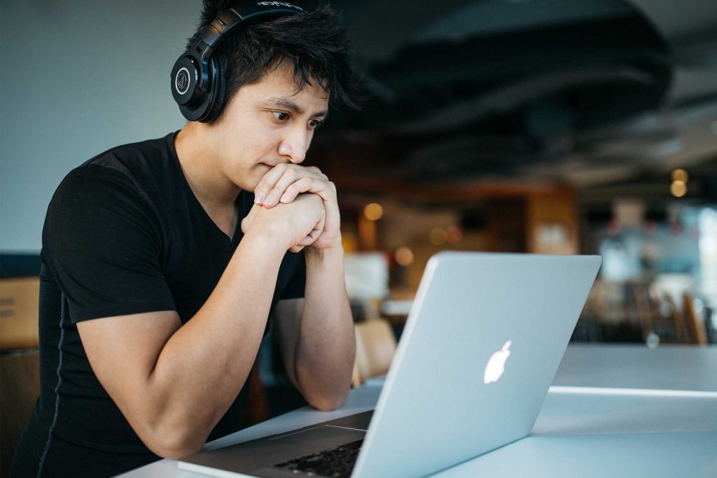 Man with headphones looking at a laptop while studying online