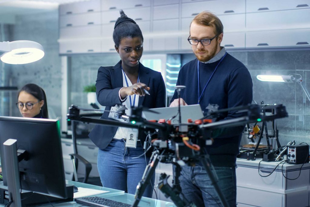 two people in front of a drone discussing notes