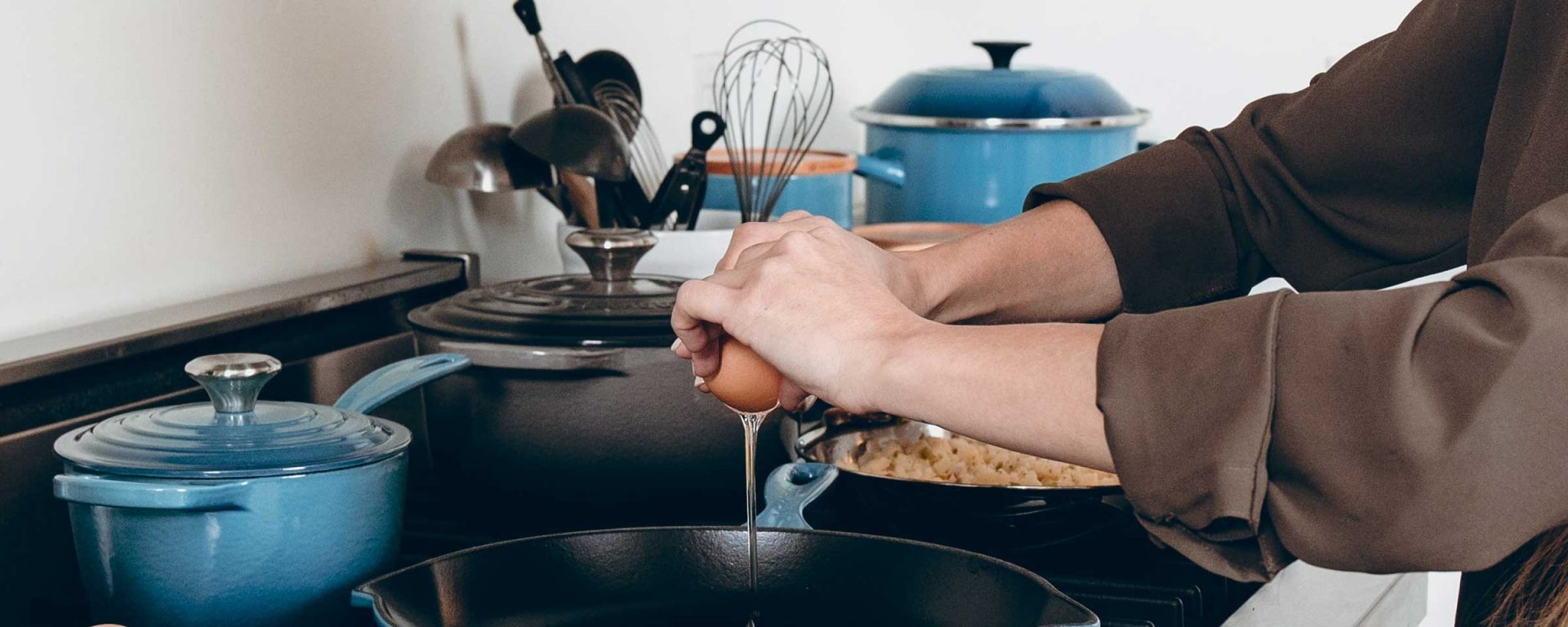 Person's hands cracking an egg into a frying pan, representing easy meals for students