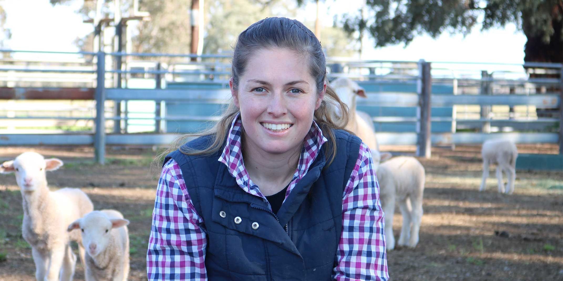 Kayla Kopp, who is doing a PhD with Charles Sturt University, in a field of lambs.