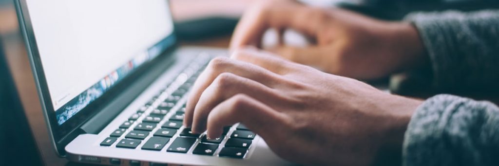 Hands at a laptop keyboard researching civil engineering job requirements