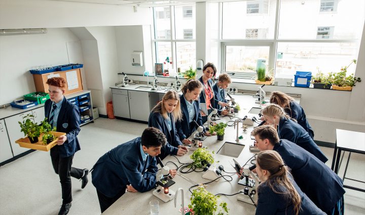 Students gathered around a bench in a science lab