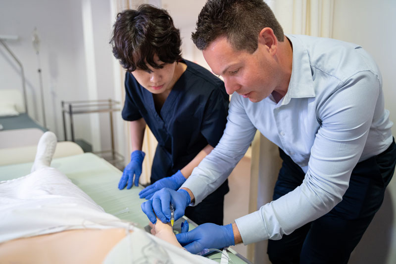 Dr. Damien Limberger showing how to insert a needle to a student