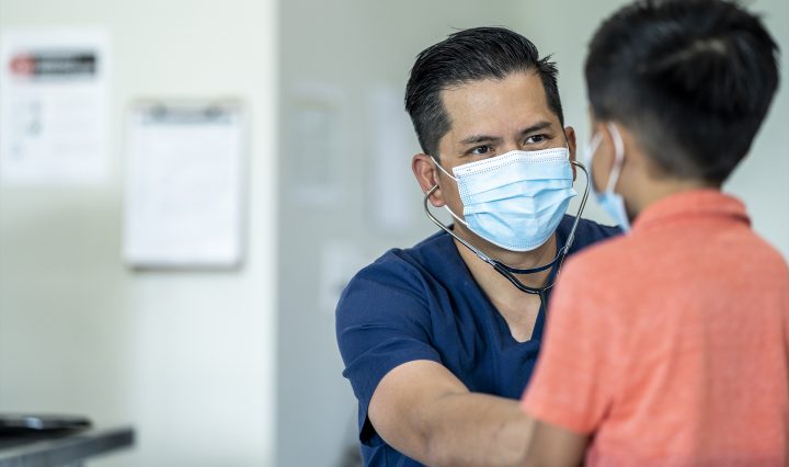 GP treating a child, both wearing face masks