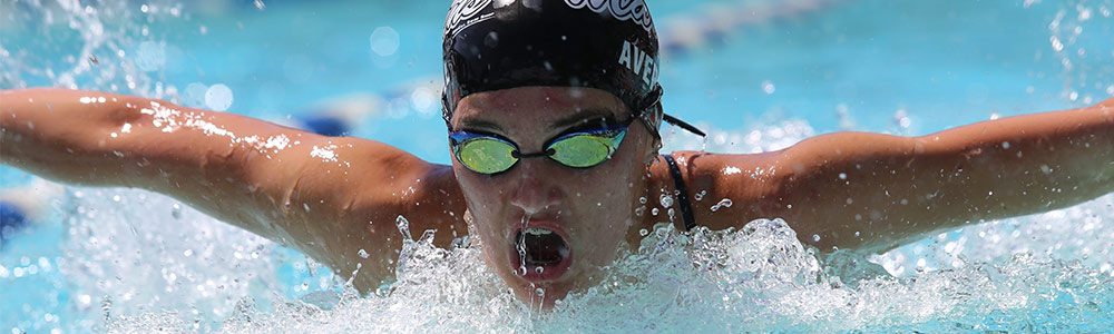 Person swimming, wearing goggles and a swimming cap