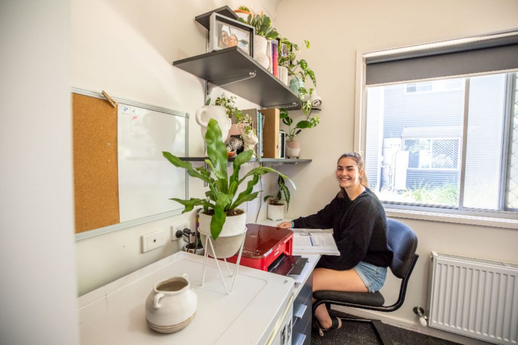 A person studying at their desk in their room