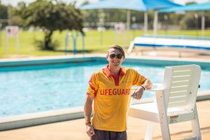 A lifeguard leaning on a seat next to the pool