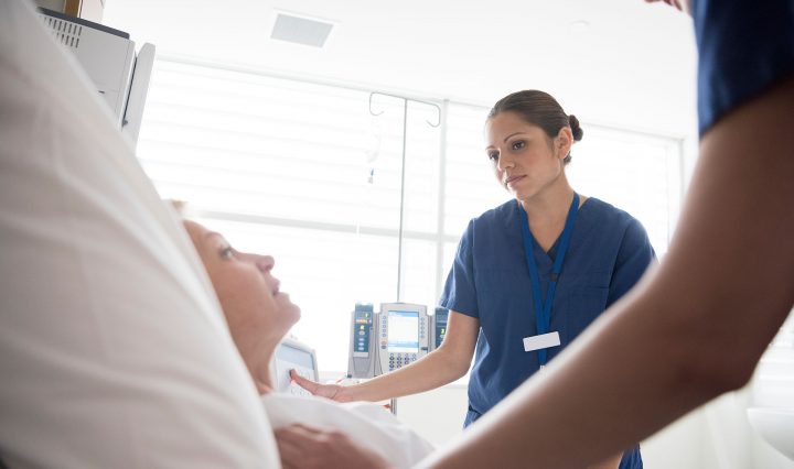 Female nurse tending to a patient in a hospital bed