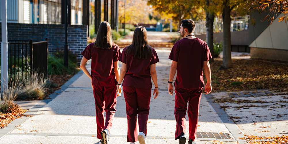 Three medicine students walking on a path on Orange campus.