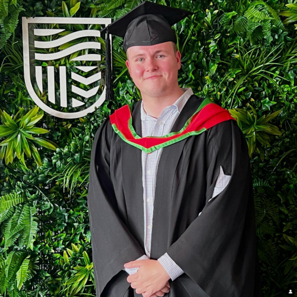 Liam in a grad cap and robe at his Charles Sturt graduation.