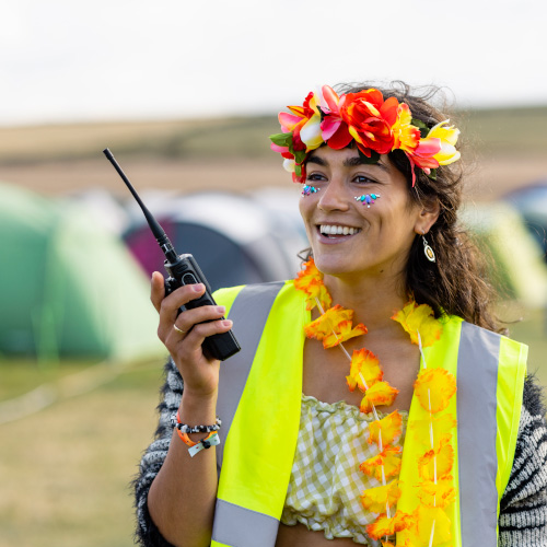 A person uses a handheld radio while wearing high-vis at an event