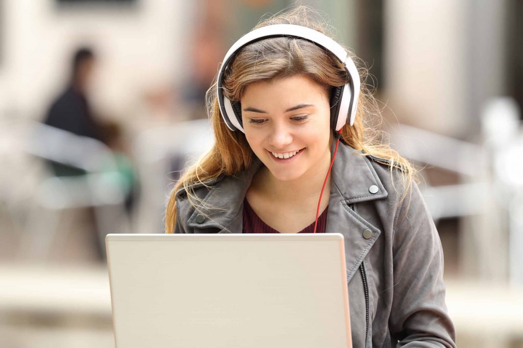 Woman listening to pop songs on headphones to help learn a language