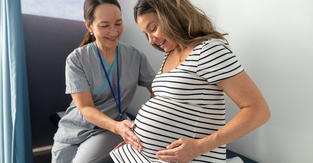A midwife feels the stomach of a pregnant person while the baby is kicking