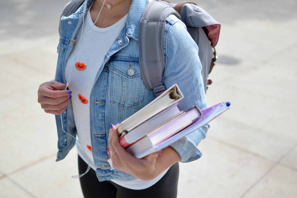 Woman carrying books while wearing headphones