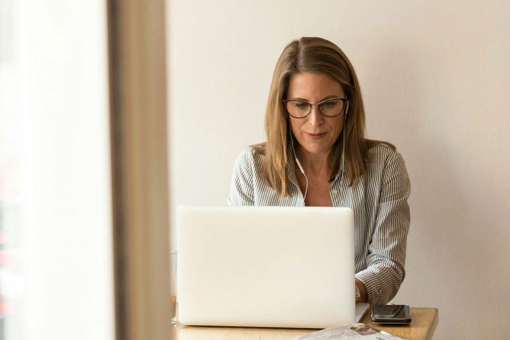 Woman with earphones writing on a laptop