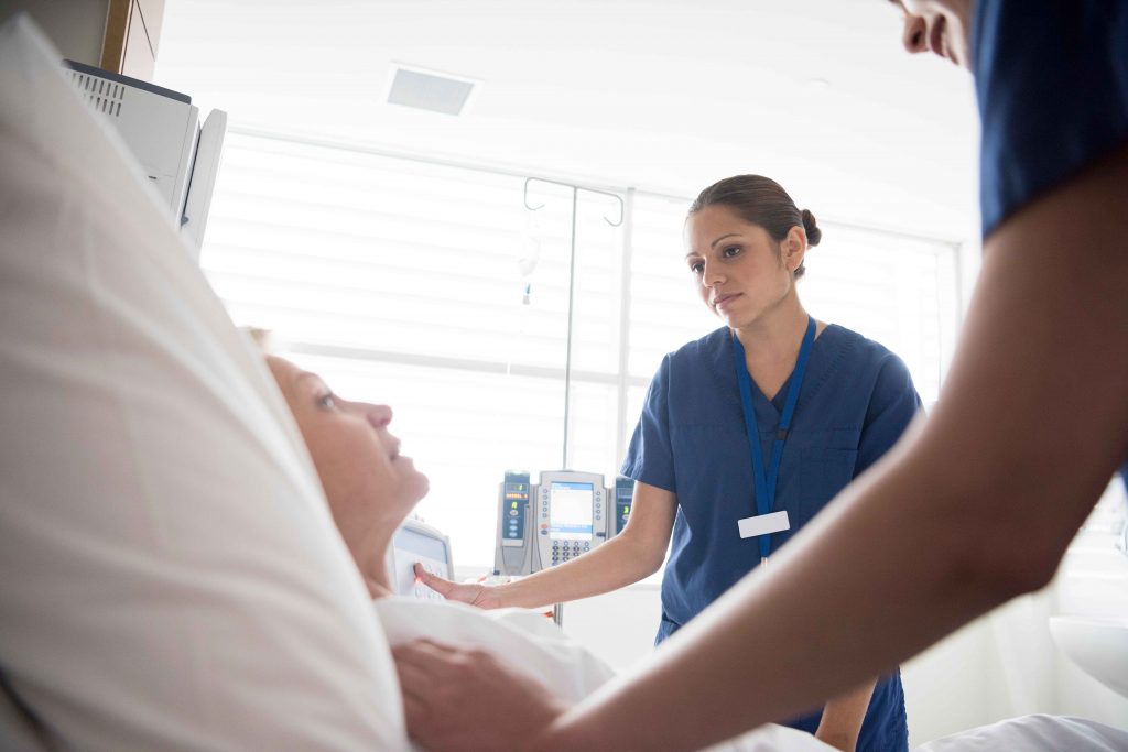 Two nurses attending a patient in bed.