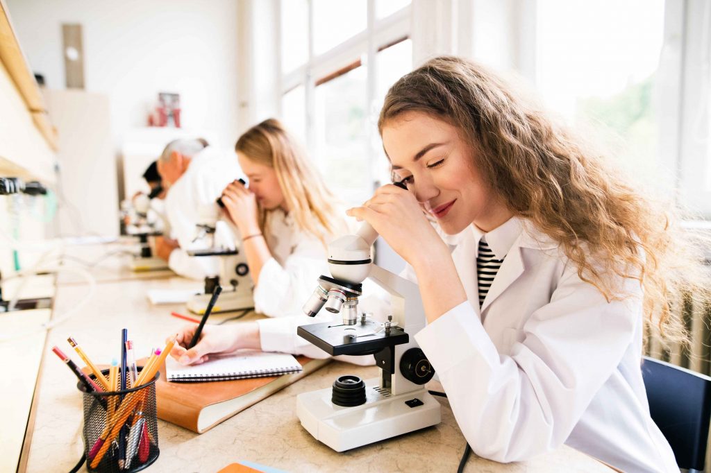 Young women looking into a microscope in a classroom