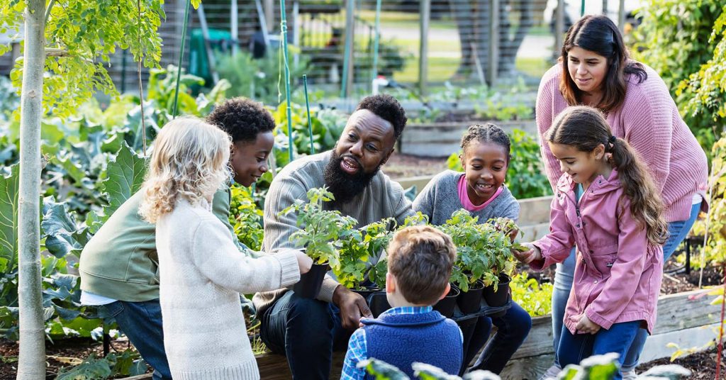 A urban horticulturist speaking to a group children in a garden