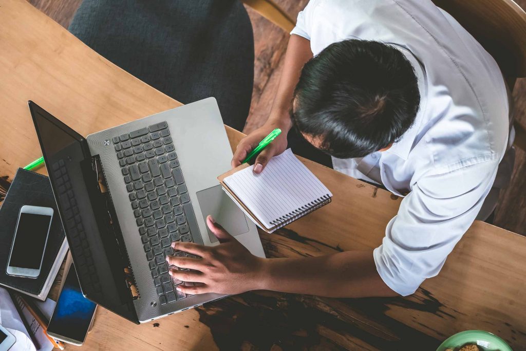 Man with a pad of paper and a laptop