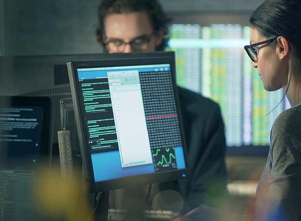 Woman and man looking at data on computer screens