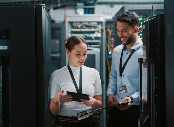 Woman and man with clipboards around computer servers