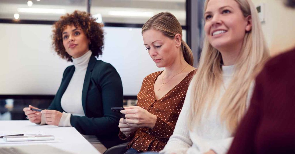 Woman using a mobile phone in a meeting