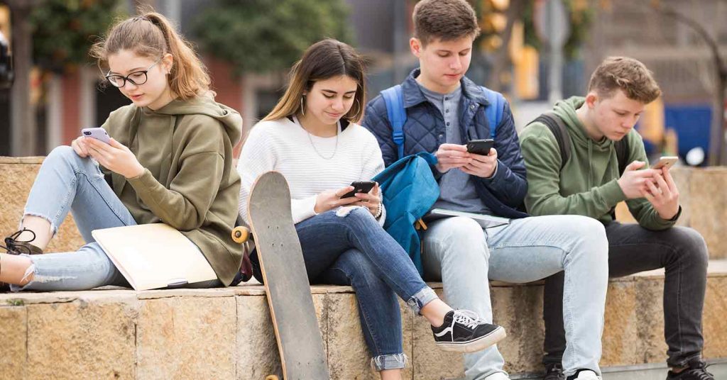 Four young people looking at their phones