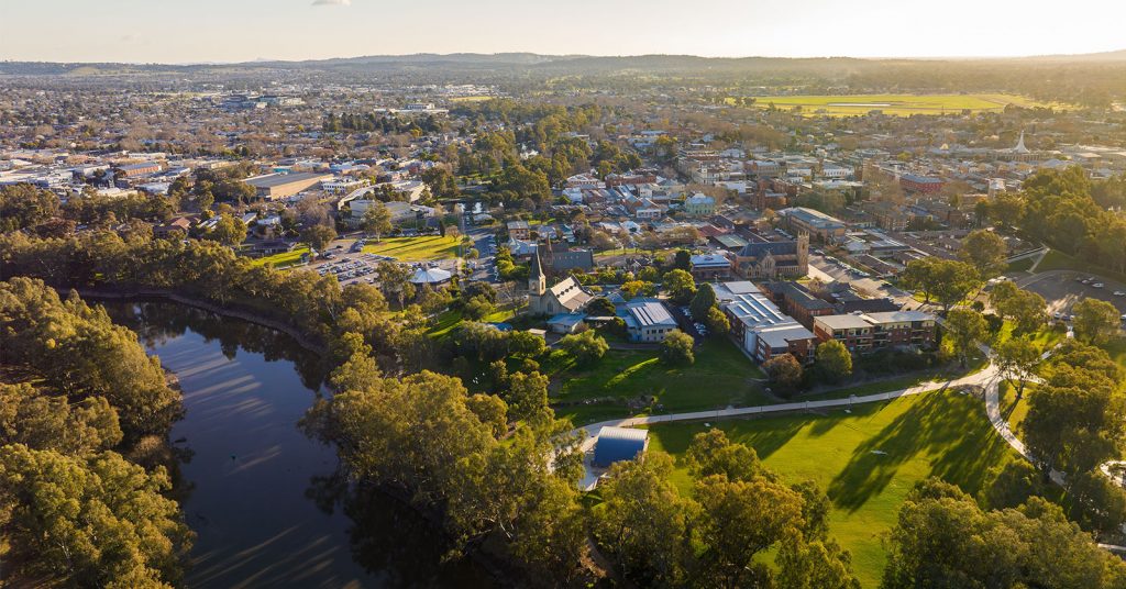 Aerial view of Wagga Wagga, Australia, featuring a lake surrounded by lush greenery and the cityscape in the background

