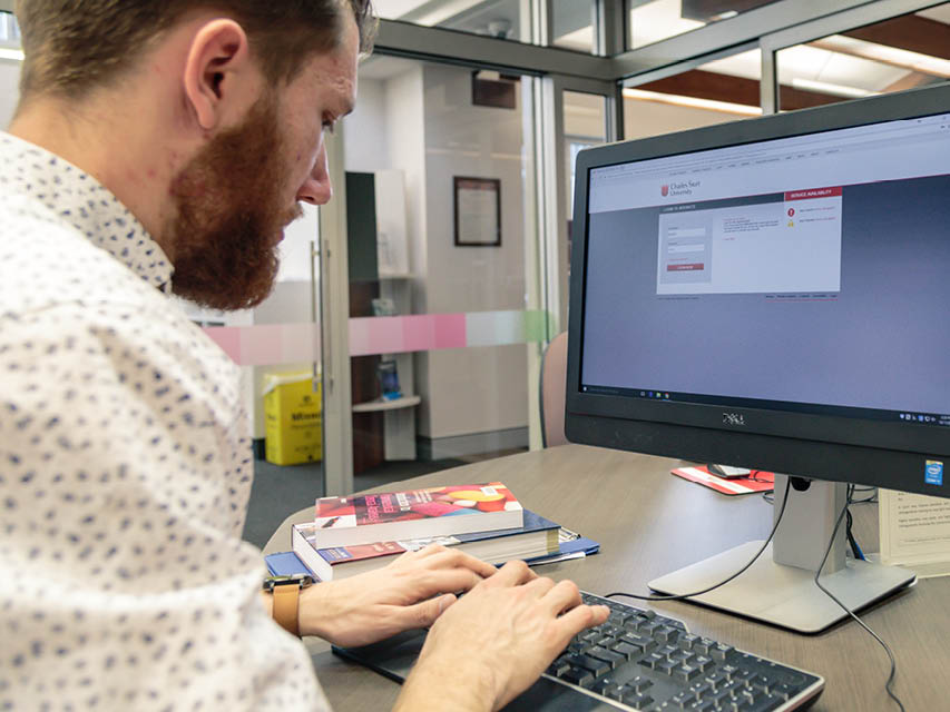 Man with books working at computer