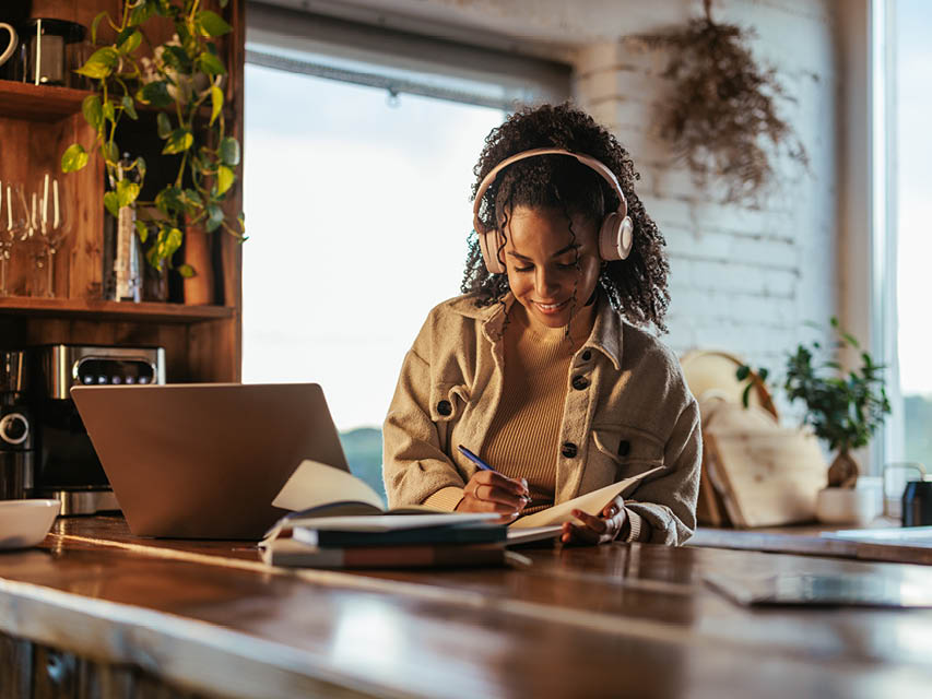 Woman with headphones writing in a notebook