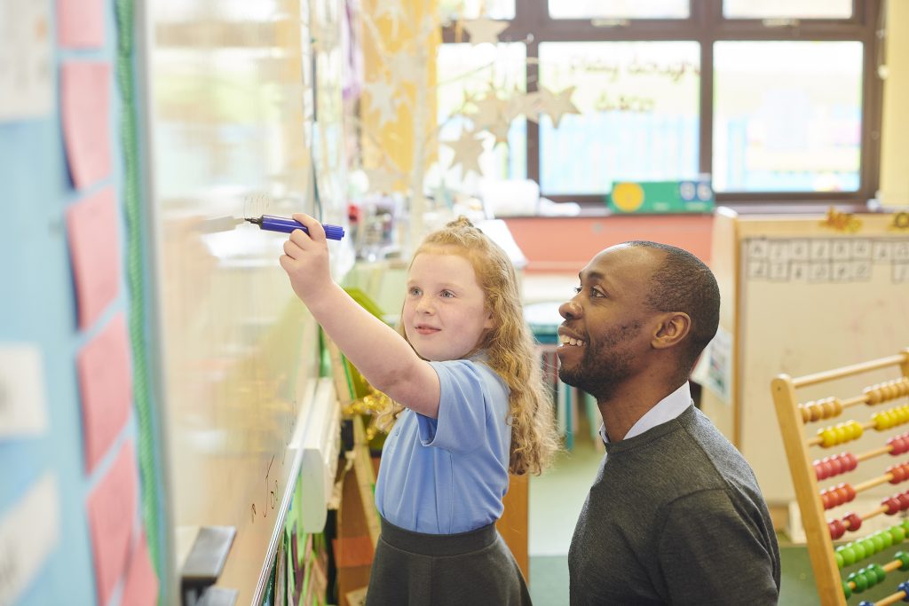 Primary teacher helping a student learn.