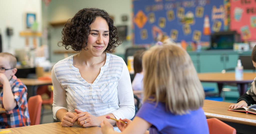 Female kindergarten teacher with student in a classroom