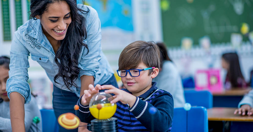 female kindergarten teacher instructing a pupil in a science experiment