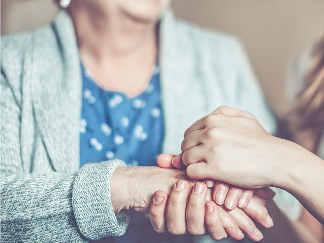 Hands clasping another person's hands