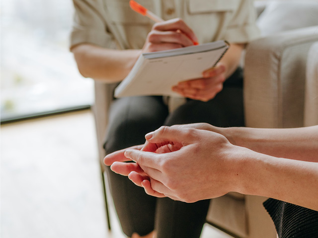 Close up of hands, one pairing clasped, the other writing