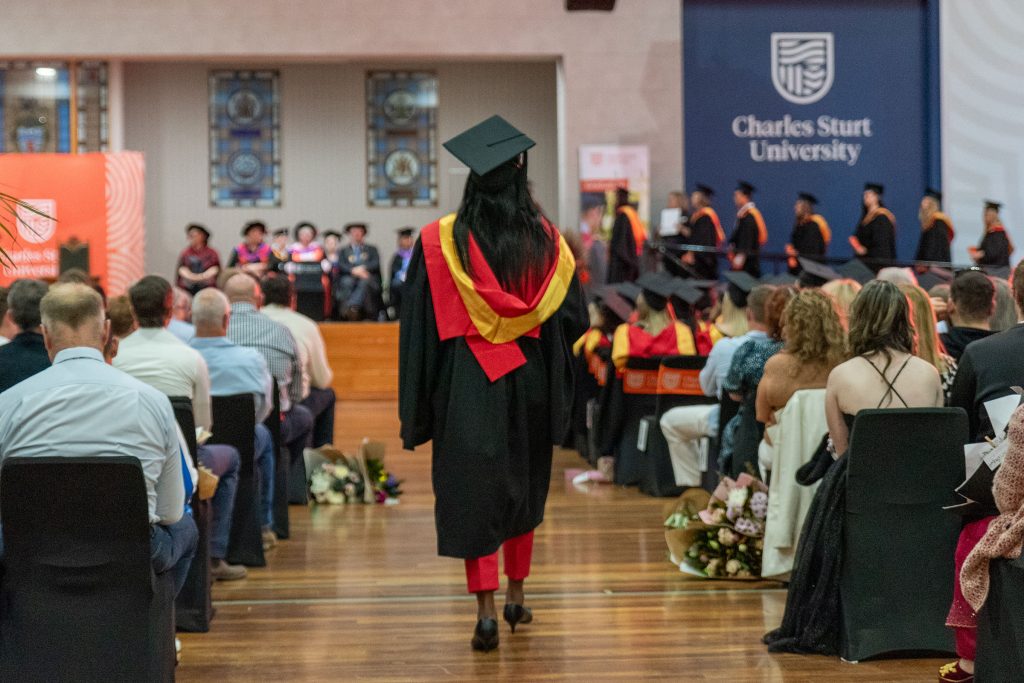 Woman walking to the stage to collect her degree at graduation